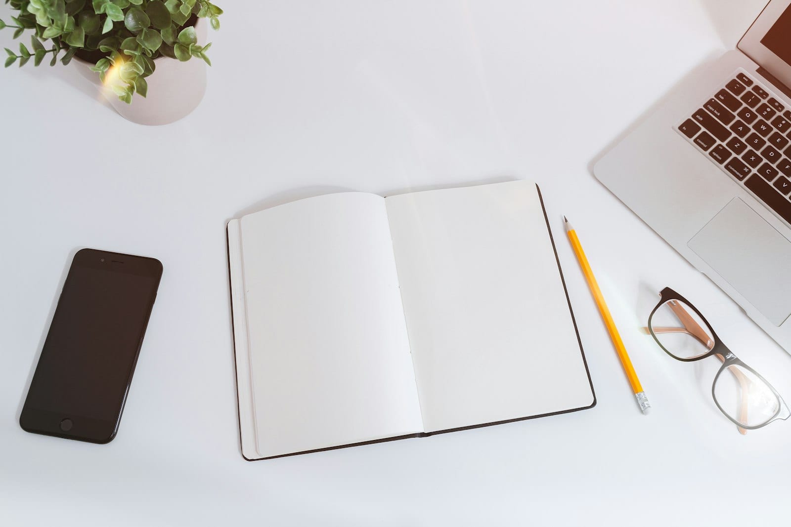 Notebook listing financial goals with calculator and laptop on a desk