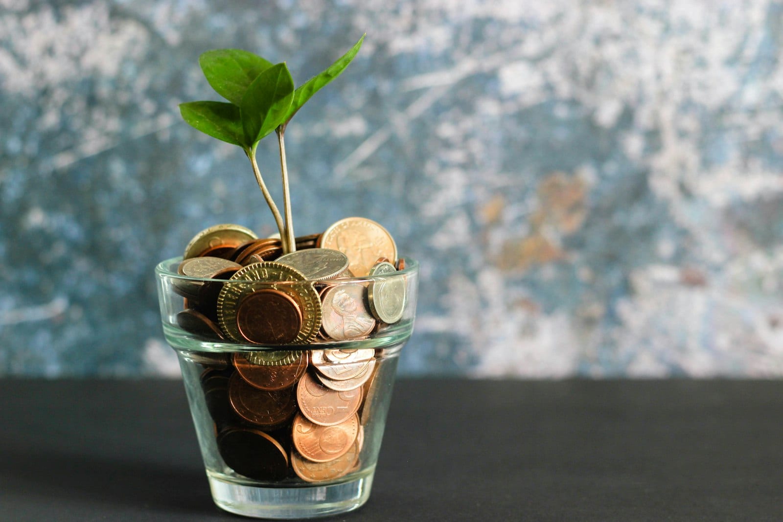 Person dropping coins into a glass jar labelled future savings